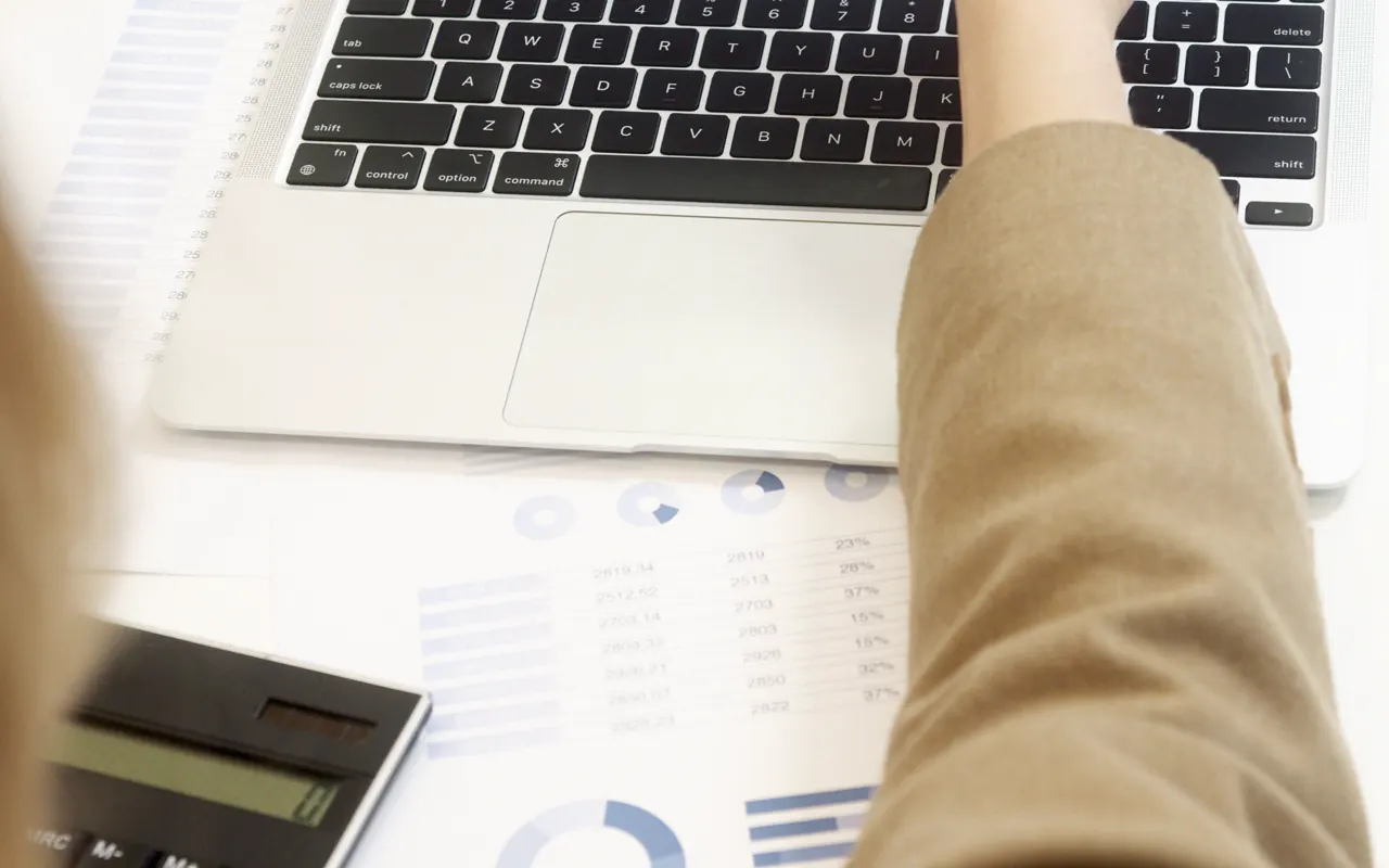 Persona revisando reportes de costos y consumo junto a una computadora.
